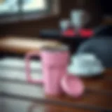 Stylish pink travel coffee mug on a wooden table with coffee inside